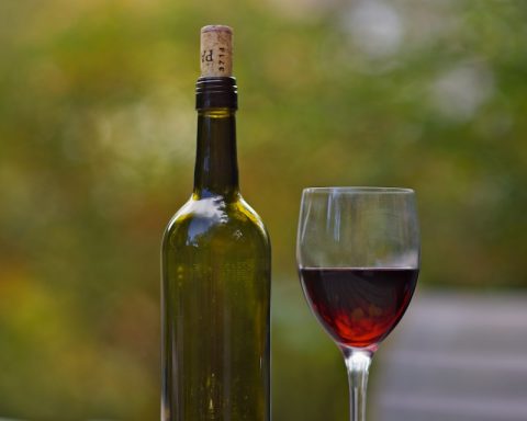 wine bottle beside wine glass on brown wooden surface