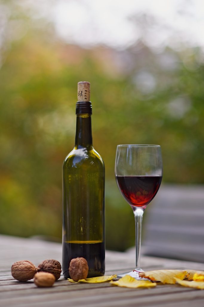 wine bottle beside wine glass on brown wooden surface