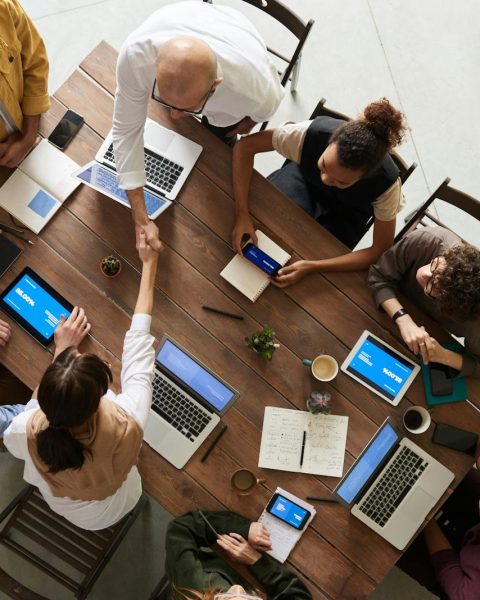 Top view of a diverse team collaborating in an office setting with laptops and tablets, promoting cooperation.