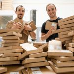 a couple of men standing next to a pile of boxes