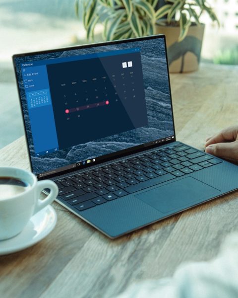 person using black laptop computer on brown wooden table