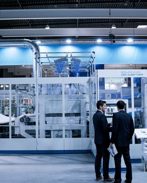 two men standing in front of glass wall