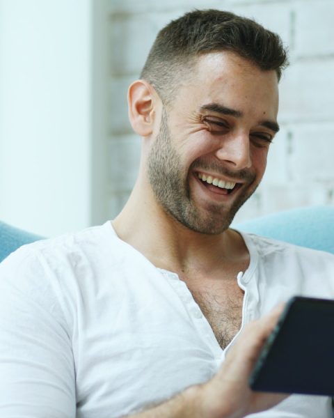 Man laughing while holding credit card and tablet.