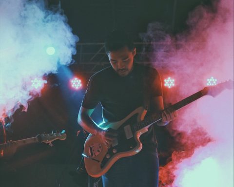 man in black crew neck t-shirt playing brown electric guitar