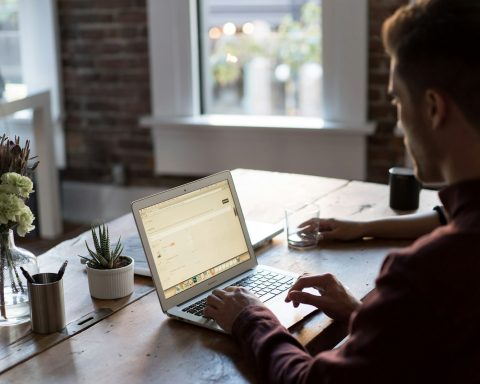 man operating laptop on top of table