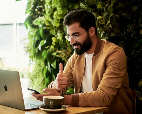 man in brown jacket sitting at a table looking at laptop