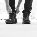 person wearing black leather lace-up boots