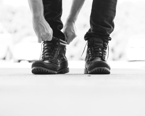 person wearing black leather lace-up boots