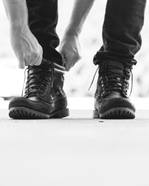 person wearing black leather lace-up boots