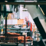 man in orange polo shirt standing in front of table