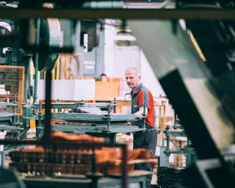 man in orange polo shirt standing in front of table