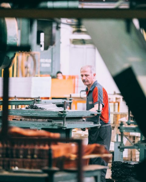 man in orange polo shirt standing in front of table