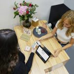two women sitting at a table with a tablet