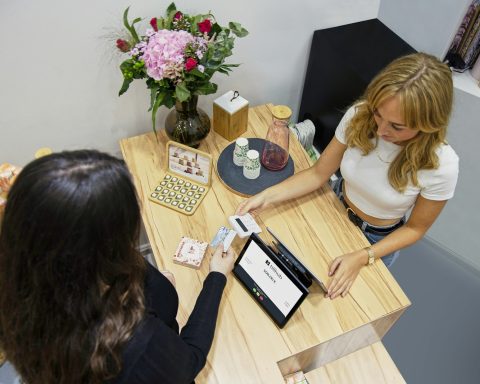 two women sitting at a table with a tablet