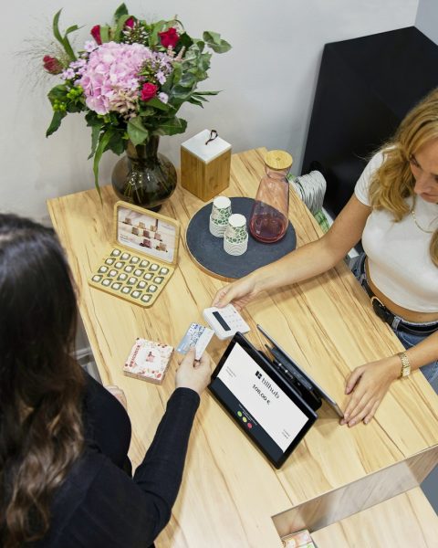 two women sitting at a table with a tablet