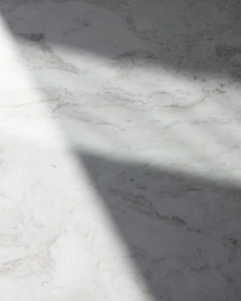 a white marble counter top with a long shadow