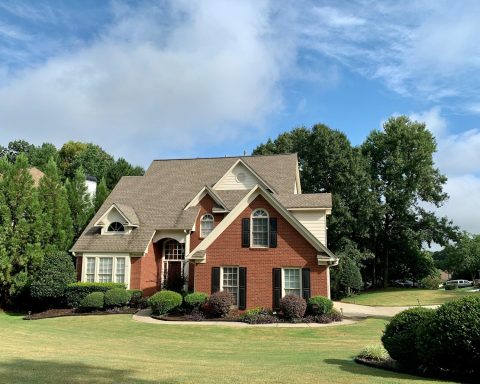 brown and white concrete house near green trees under blue sky during daytime