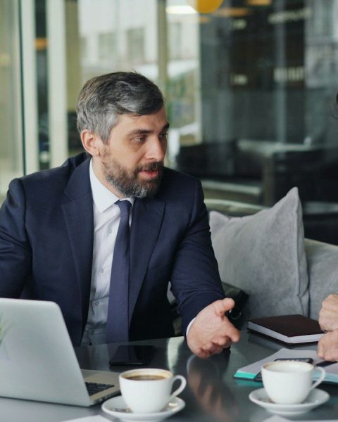 a couple of men sitting at a table in front of a laptop