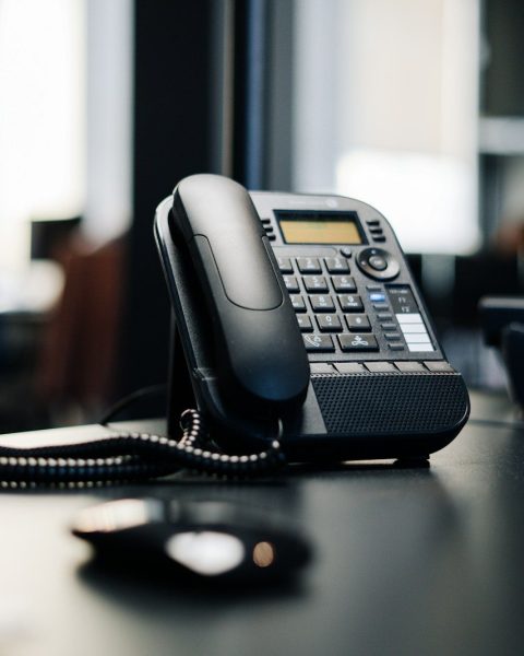 black ip desk phone on black wooden table