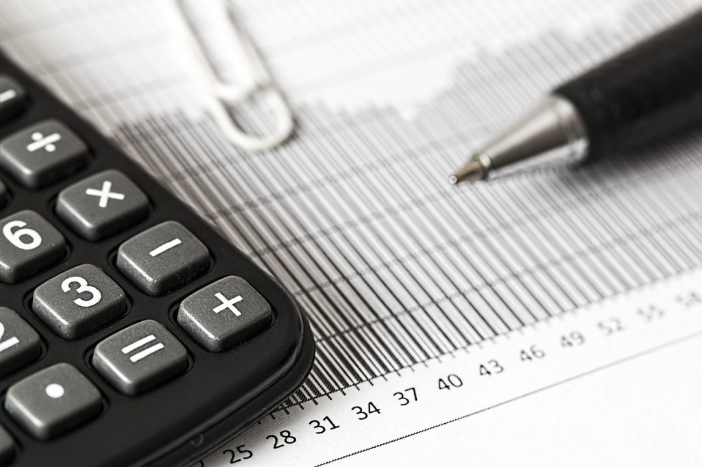 Ondernemer die met een rekenmachine en financieel overzicht een investeringsbeslissing berekent