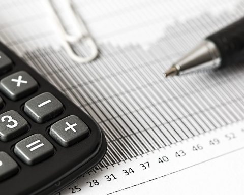 Ondernemer die met een rekenmachine en financieel overzicht een investeringsbeslissing berekent