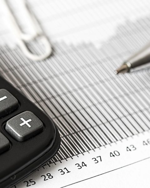 Ondernemer die met een rekenmachine en financieel overzicht een investeringsbeslissing berekent