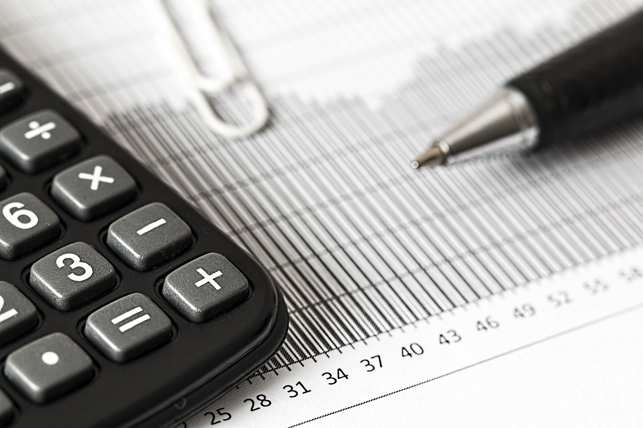 Ondernemer die met een rekenmachine en financieel overzicht een investeringsbeslissing berekent