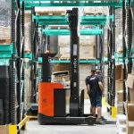 A man standing in a warehouse with a fork lift