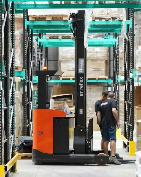 A man standing in a warehouse with a fork lift