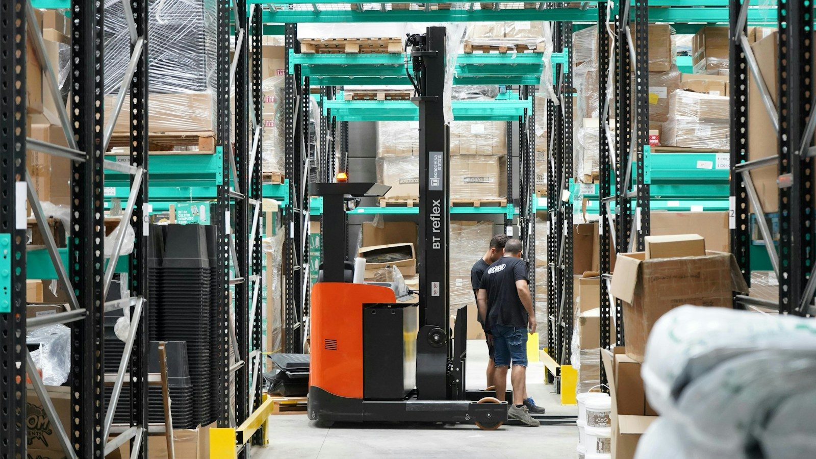 A man standing in a warehouse with a fork lift