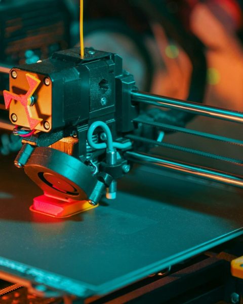 3D printer creating a red object with yellow filament