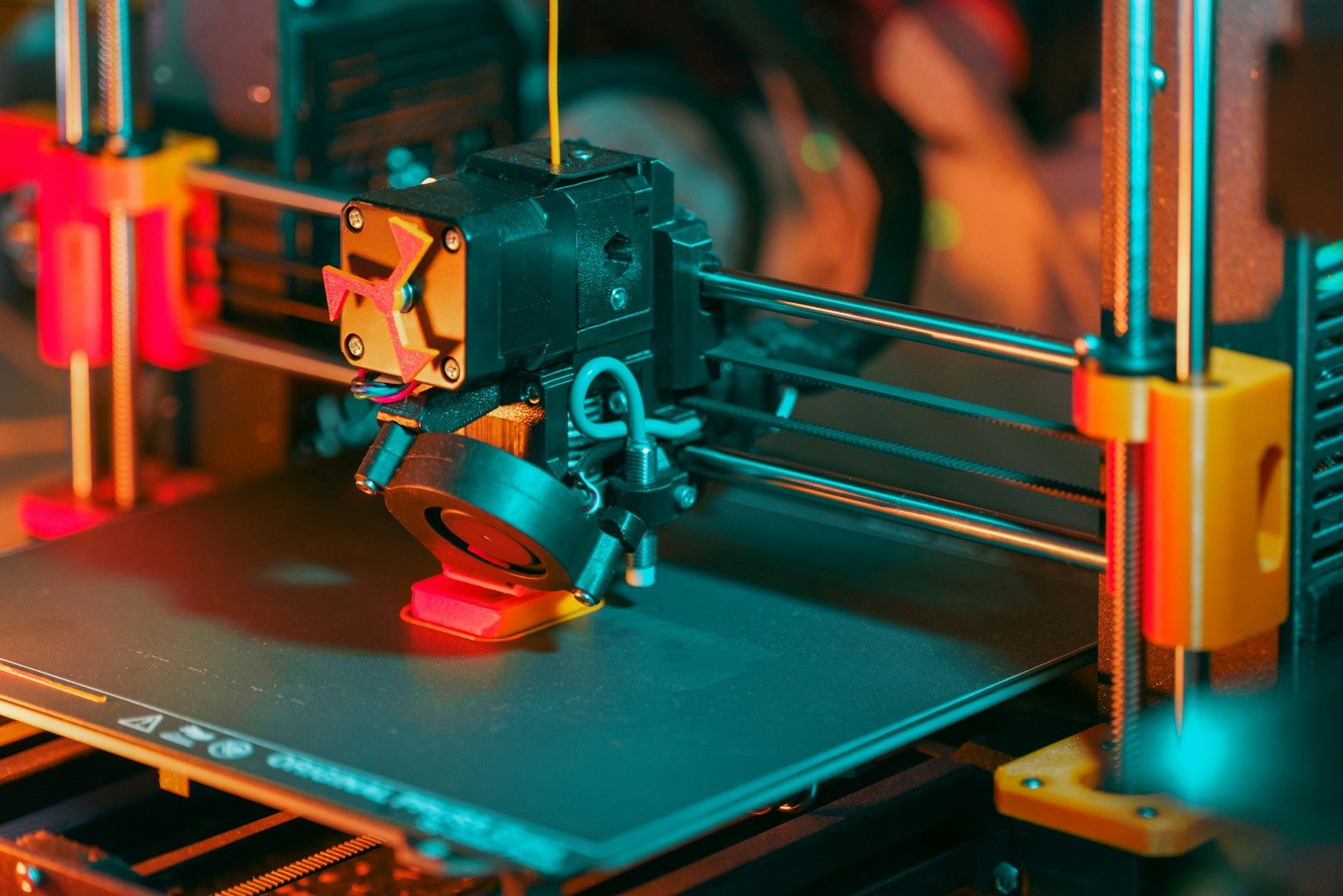 3D printer creating a red object with yellow filament